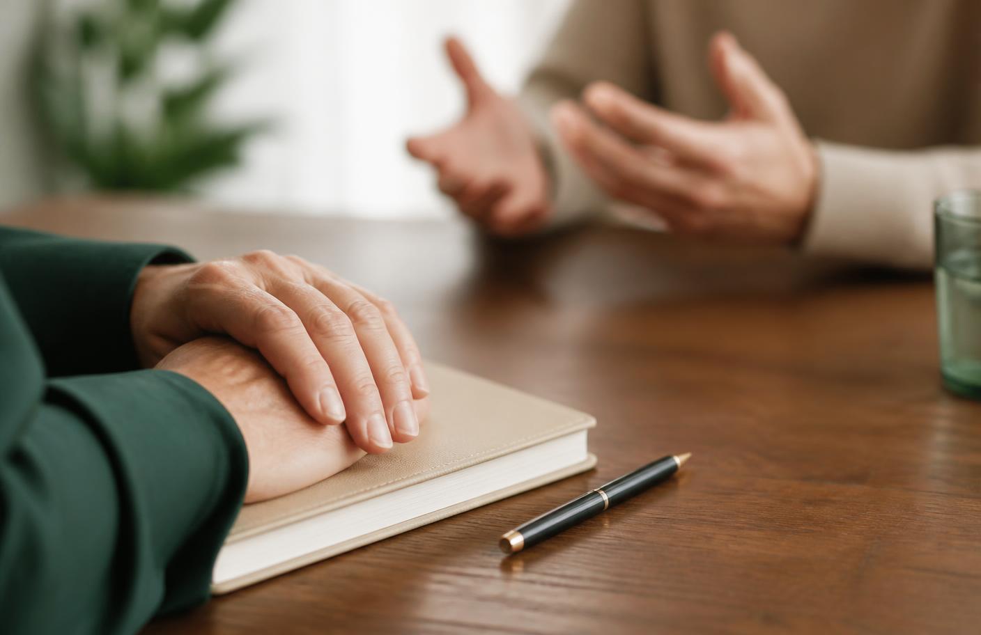 Handen bij een open notitieboek tijdens een gesprek