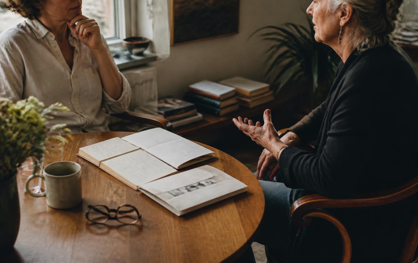 Gesprek aan een houten tafel met notitieboeken en warm daglicht